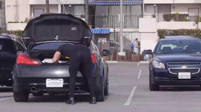 Lo scherzo dei leggins Un uomo sistema delle borse nel baule della sua auto: scherzo dei leggins