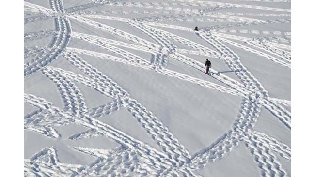 L'artista Simon Beck mentre cammina sulla neve