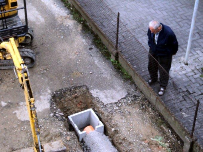 Un pensionato guarda attentamente i lavori in corso