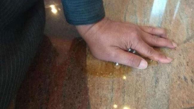 Uomo protesta contro multinazionale incollandosi al loro pavimento La mano di Hamid incollata al pavimento