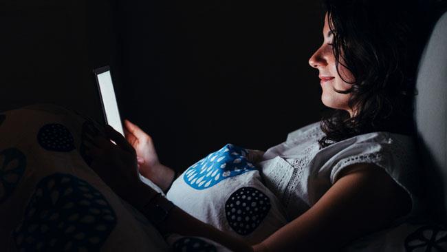 Immagini della buonanotte, le più divertenti da scaricare gratis Una ragazza che nel buoi guarda lo smartphone - Immagini della buonanotte, le più divertenti da scar
