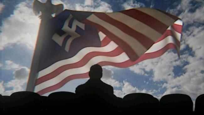 Un personaggio della serie TV vicino a una bandiera Un'immagine estratta da The Man in the High Castle