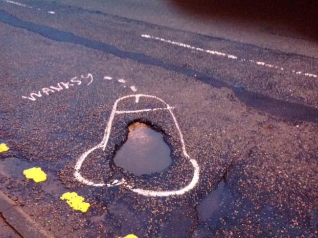 L'artista Wanksy disegna peni attorno alle buche Pene disegnato da Wanksy attorno a una buca