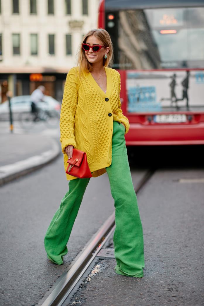 Pantaloni palazzo indossati con maxi cardigan giallo e pochette Pantaloni palazzo abbinati a maxi cardigan giallo