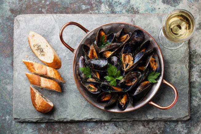 Ricetta dell'impepata di cozze tradizionale Impepata di cozze su tagliere con bicchiere di vino