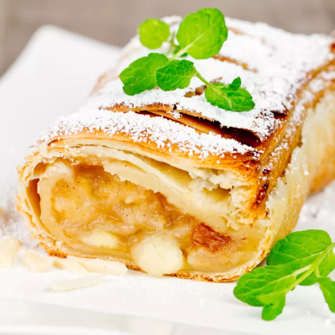 Strudel di mele, un dolce tipico del Trentino Alto Adige con mele renette e frutta secca Strudel di mele decorato con zucchero a velo e foglioline