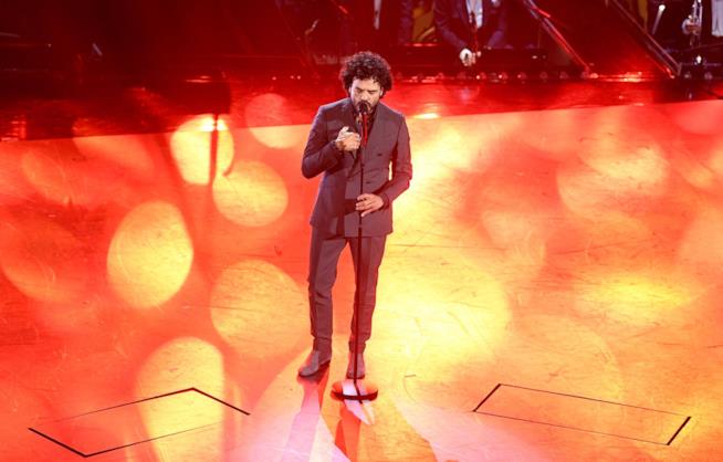 Il cantante Francesco Renga Francesco Renga, in piedi, canta di fronte al microfono, su sfondo arancione