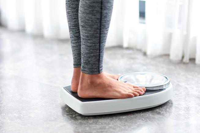 La dieta Sirt fa perdere peso senza fatica Dettaglio di una ragazza su una bilancia della quale si vedono solo le gambe
