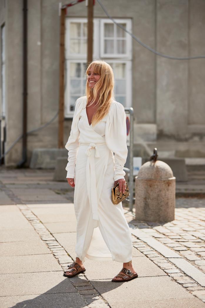 Jumpsuit bianca indossata con ciabatte Birkenstock e pochette animalier Jumpsuit bianca abbinata a ciabatte Birkenstock e pochette animalier