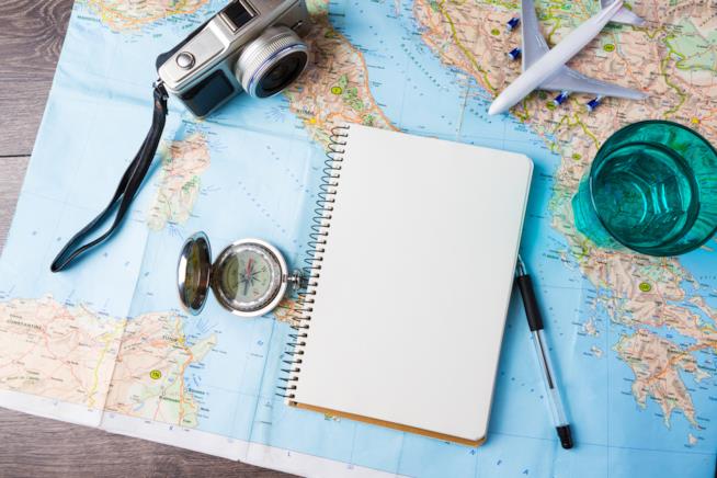Le città più belle per una vacanza da sola Una cartina geografica dove sopra sono posati diversi oggetti inerenti al tema viaggio