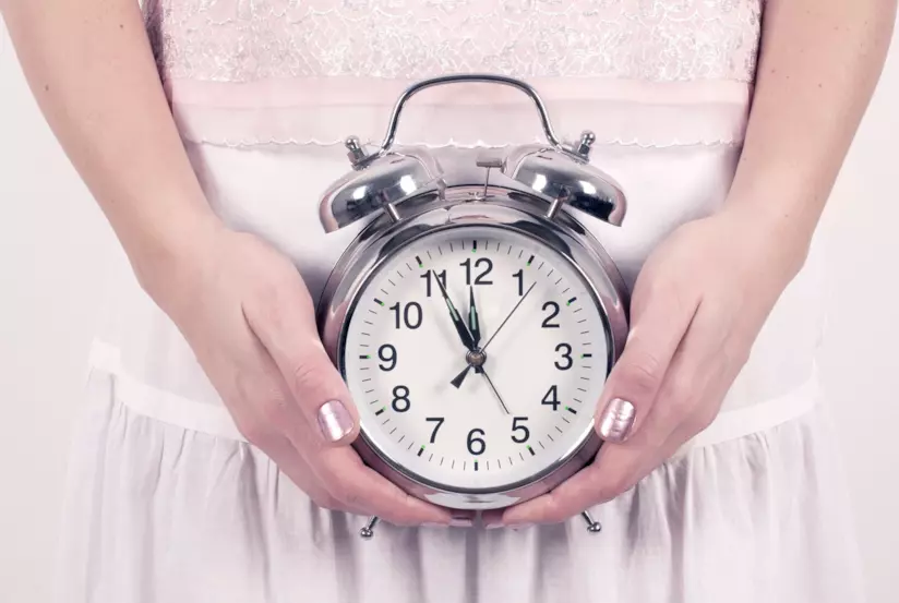 Si può allontanare il momento della menopausa Donna regge una sveglia con entrambe le mani