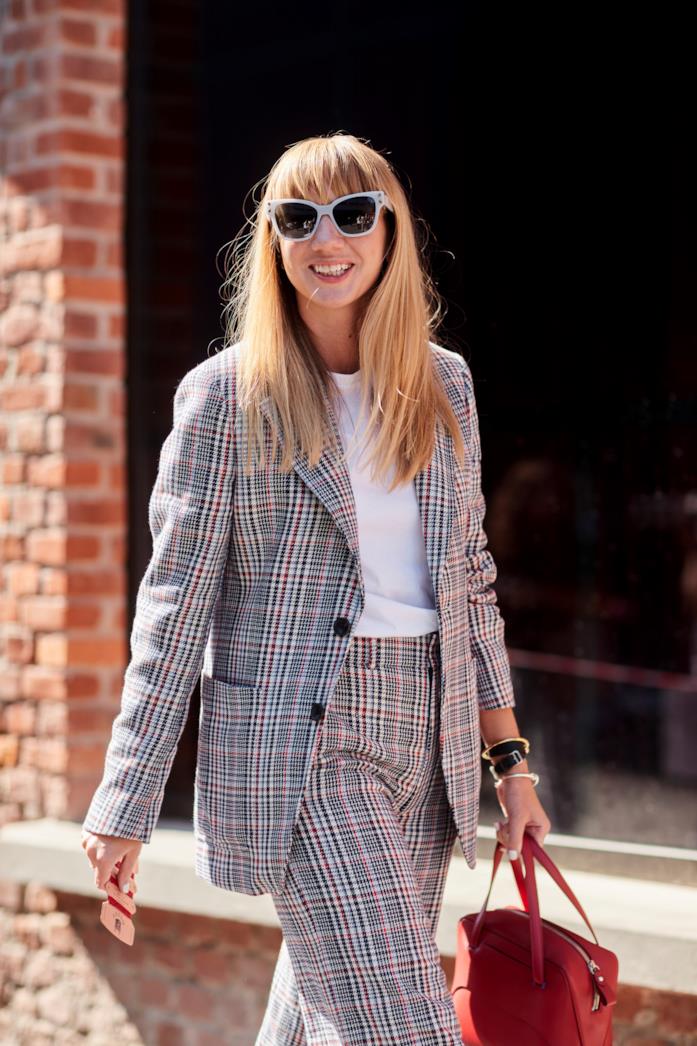 Un completo coordinato indossato con t-shirt bianca e handbag rossa Blazer e pantaloni a quadri indossati con t-shirt e borsa a mano