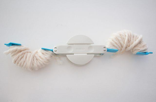 Arrotolare il filo alle due estremità del pom pom maker Dettaglio del pom pom maker con le estremità aperte e il filo arrotolato intorno ad esse