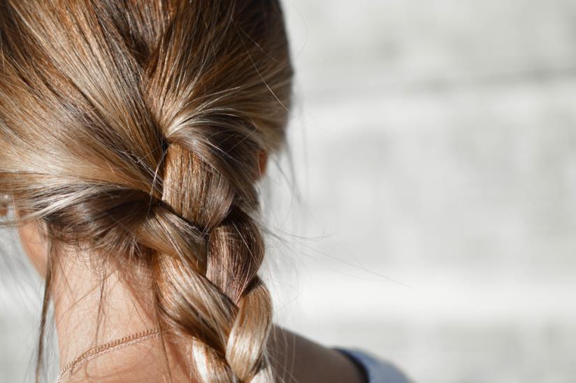 Capelli biondi, ecco tutti i segreti per avere una chioma perfetta. Una donna di spalle con una treccia.