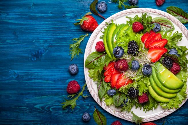 Estate 2017 a tavola con colori, bio e natura piatto colorato con insalata, avocado, frutti di bosco appoggiato su un piano azzurro