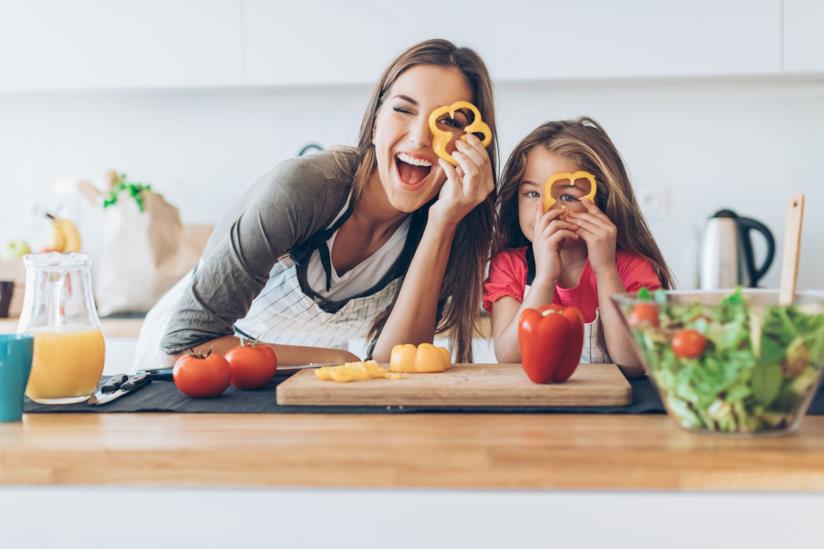 Gli oggetti più bizzarri da usare in cucina Mamma e figlia in cucina che giocano con le verdure tagliate