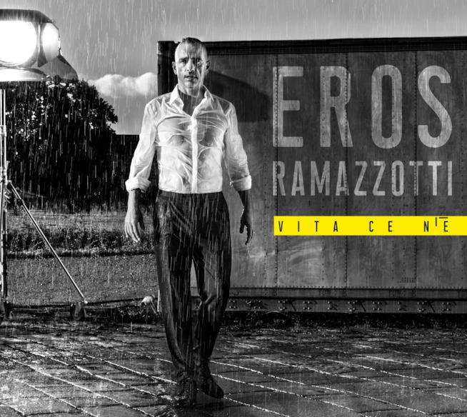Vita ce n'è Eros Ramazzotti, in bianco e nero, in piedi, sotto la pioggia con la scritta Vita ce n'è