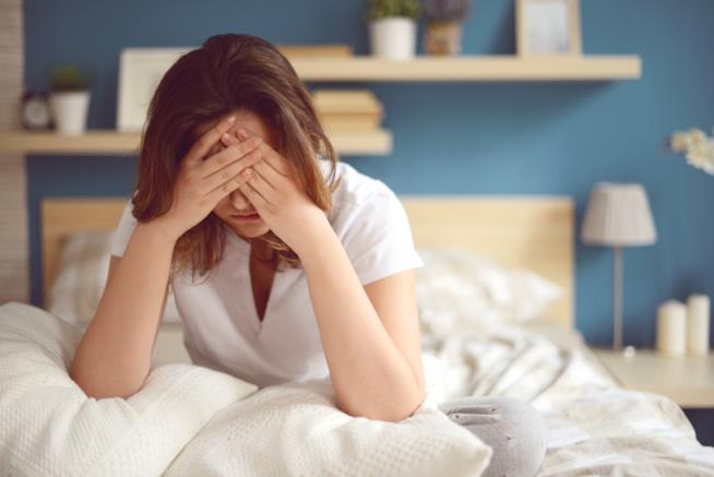 La fibromialgia può essere curata con una semplice pomata Una ragazza sul letto con le mani sul viso in una situazione di sofferenza