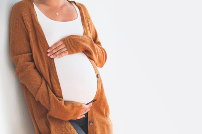 Test di gravidanza fai da te con dentifricio e urina Donna incinta appoggiata a un muro con le mani sul ventre prominente