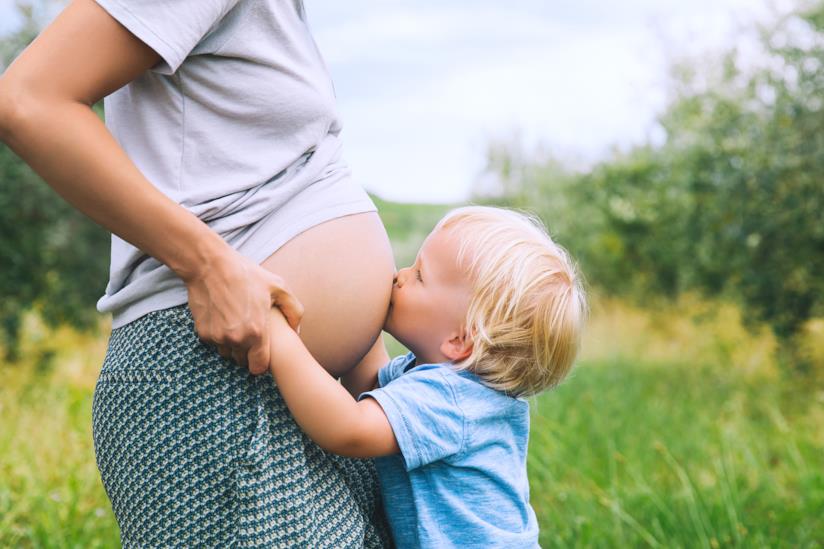 Una bimba ascolta il pancione della mamma Una mamma incinta con una bambina