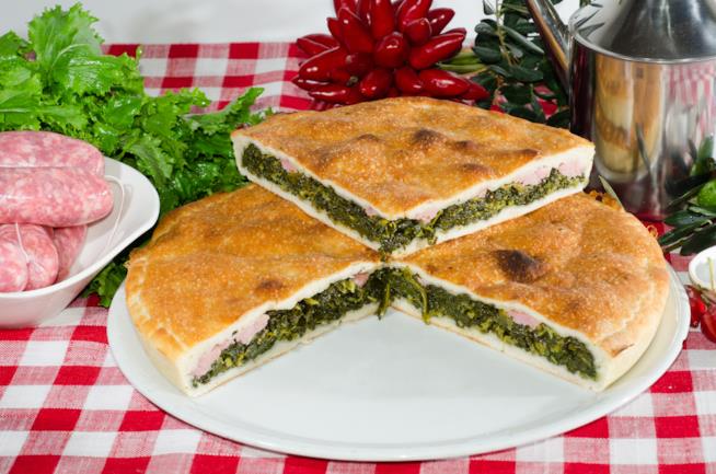 Pizza rustica napoletana: la ricetta Piatto bianco da pizza con all'interno focaccia rustica farcita con salsiccia e friarielli