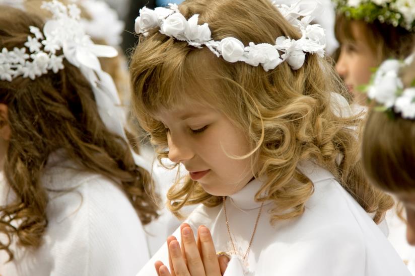 Frasi per la prima comunione Bambina con l'abito della prima comunione in preghiera