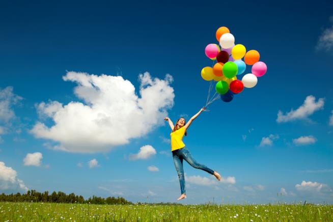 Mai più stress causato dal cambio di stagione Una donna che salta con palloncini colorati in mano