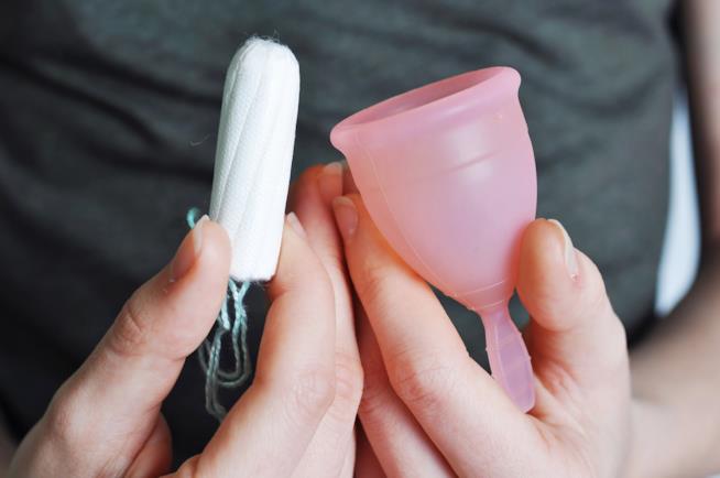 Coppetta mestruale meno igienica del tampone Ragazza tiene in mano coppetta mestruale e tampone