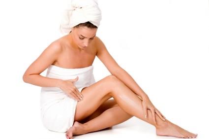 Olio di cocco come crema idratante Donna che applica olio di cocco sulle gambe