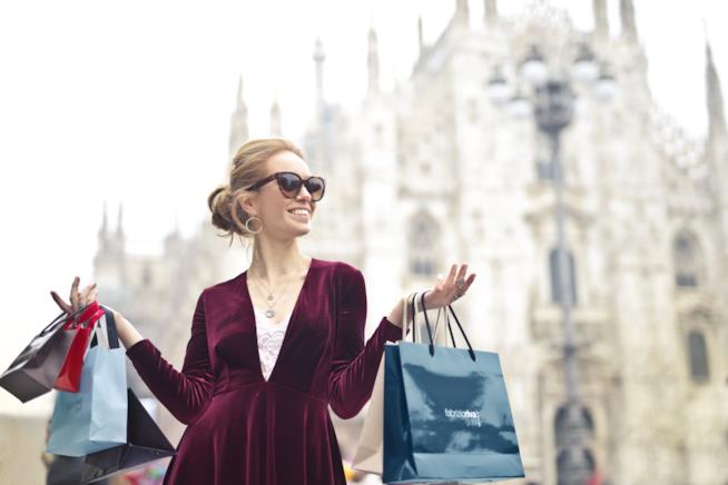 Il nuovo brand di Amazon per le occasioni importanti Una donna cammina con le buste dello shopping