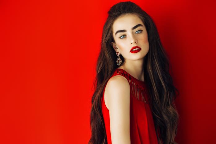 Gli outfit perfetti per ogni matrimonio Ragazza dagli occhi azzurri indossa abito rosso su sfondo rosso