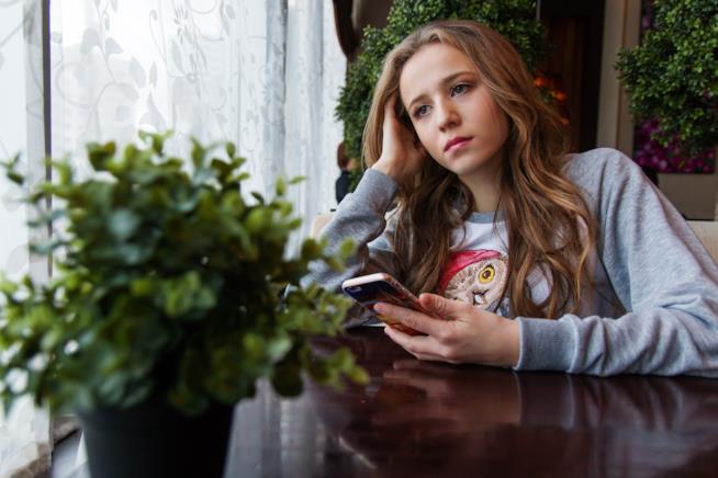 Una ragazza in un café con uno smartphone Una ragazza con in mano uno smartphone
