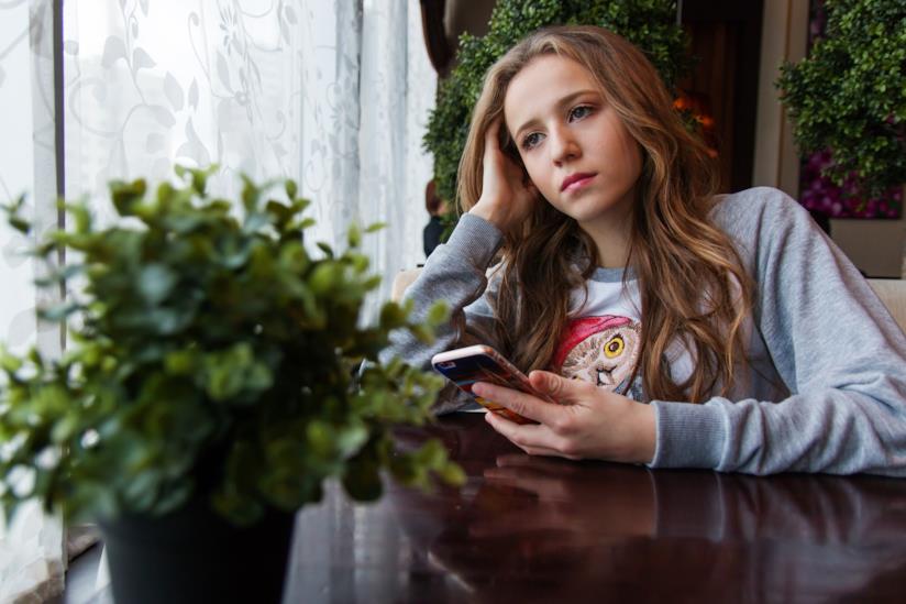 Una ragazza in un café con uno smartphone Una ragazza con in mano uno smartphone