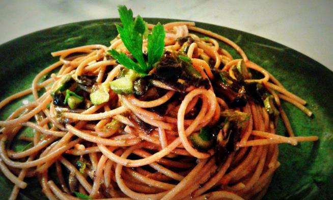Spaghetti integrali conditi con una salsa di alghe miste, fiori di zucca, capperi, olive, zucchine e decorati con foglie di prezzemolo fresco Spaghetti integrali con sugo di alghe e fiori di zucca