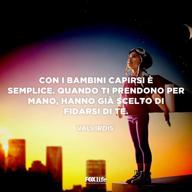 Frase sul capire i bambini Bambino in cima a un grattacielo con ali di carta