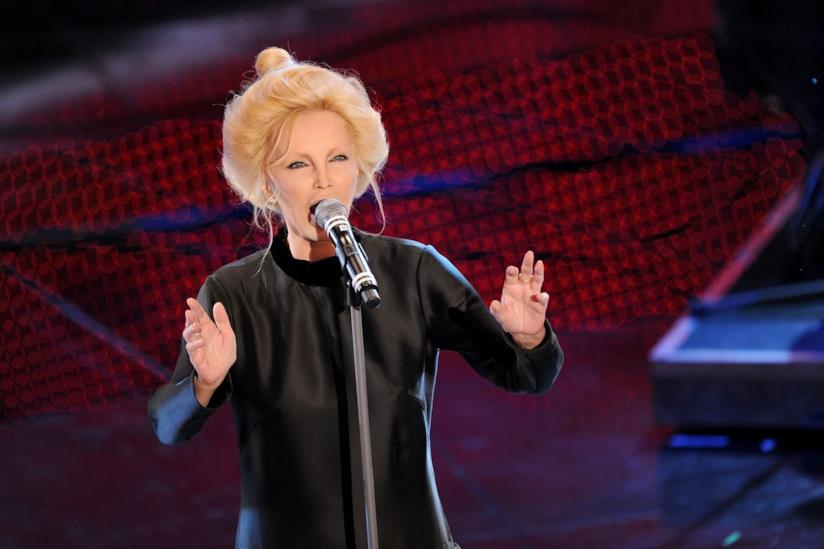 La cantante Patty Pravo Patty Pravo, in piedi, in nero, canta al microfono su uno sfondo rosso