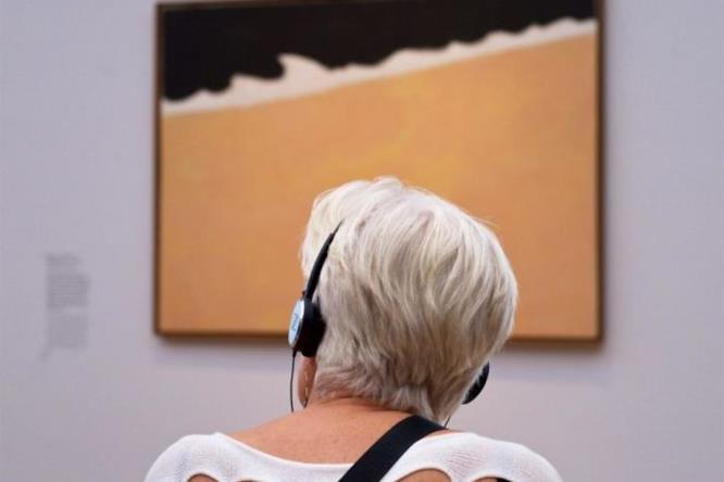 La maglia ed il quadro Una donna con delle cuffie seduta di fronte ad un quadro
