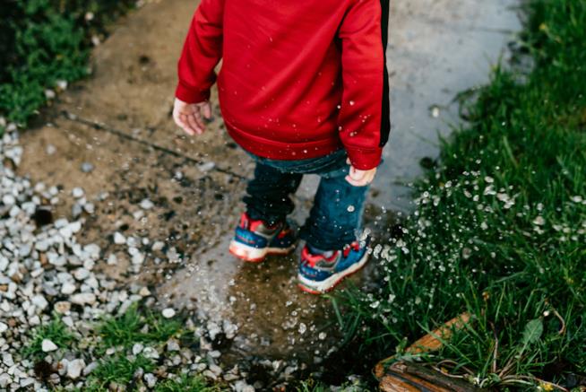 Stivali di gomma allegri, ombrelli e giacche che cambiano colore: i bambini ameranno stare all'aperto quando piove Bambino che salta nelle pozzanghere