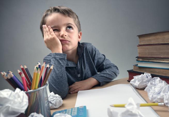 Problemi nella scrittura: che cos’è e come curarla Bambino che fa i compiti in difficoltà