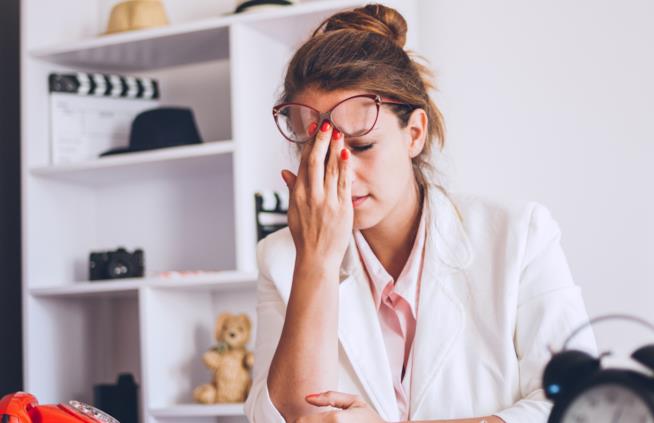 Lo stress femminile causa danni alla salute delle donne Una donna stressata si massaggia la fronte