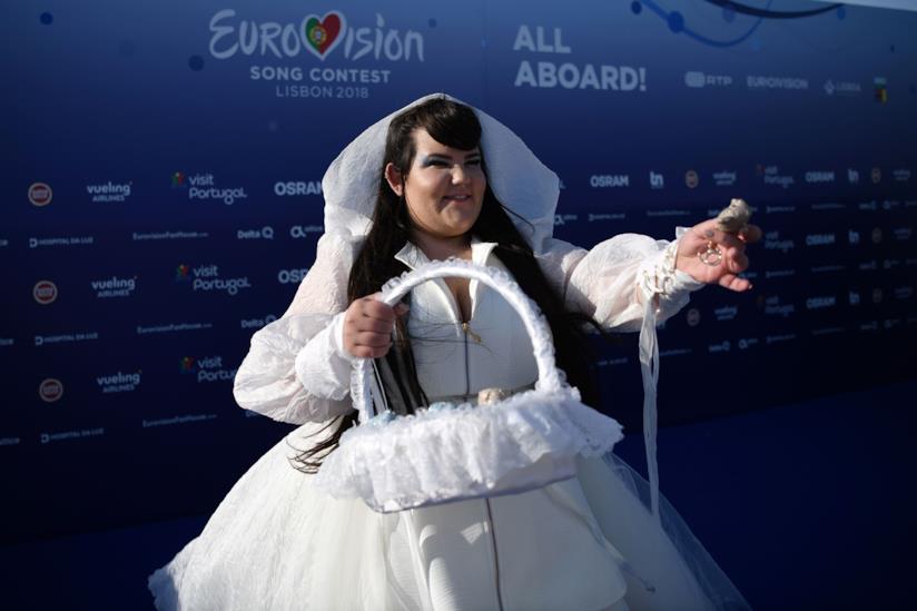 La cantante israeliana Netta La cantante Netta, vestita di bianco, con in mano un cestino e lo sfondo blu dell'Eurovision