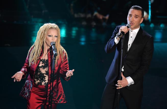 Patty Pravo e Briga Patty Pravo in rosso e Briga in nero, in piedi, davanti al microfono
