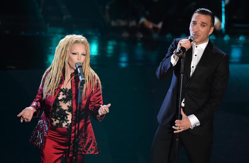 Patty Pravo e Briga Patty Pravo in rosso e Briga in nero, in piedi, davanti al microfono