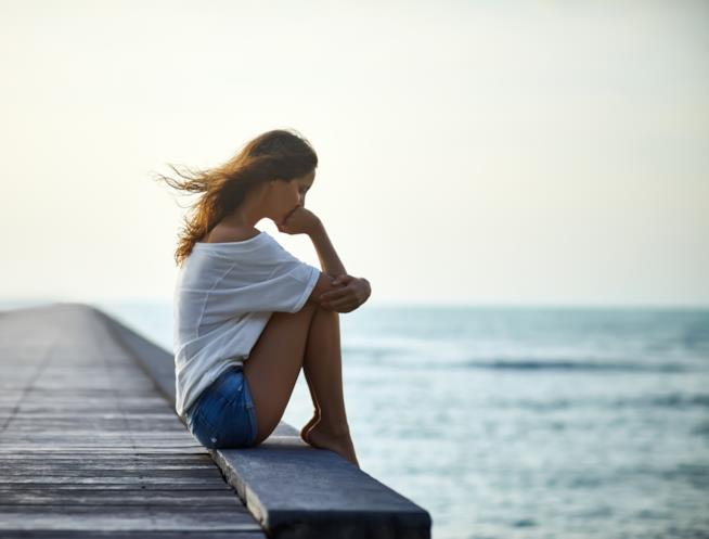 Come superare il rifiuto di un uomo Ragazza sola seduta su un pontile