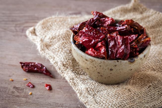 Peperoni cruschi: la ricetta Primo piano di peperoncini rossi croccanti in ciotola di pietra su tavolo da cucina in legno