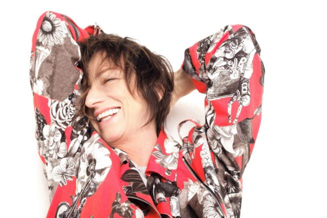 Gianna Nannini oggi compie gli anni Primo piano della Nannini, sorridente, con una maglia con fantasia floreale, braccia dentro la nuca