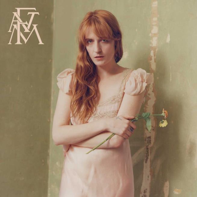 High As Hope dei Florence + The Machine Florence Welch in piedi, vestita di rosa, con due fiori in mano