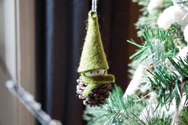 Elfo fai da te realizzato con pigna e feltro L'elfo fai da te appeso ai rami di un albero di Natale