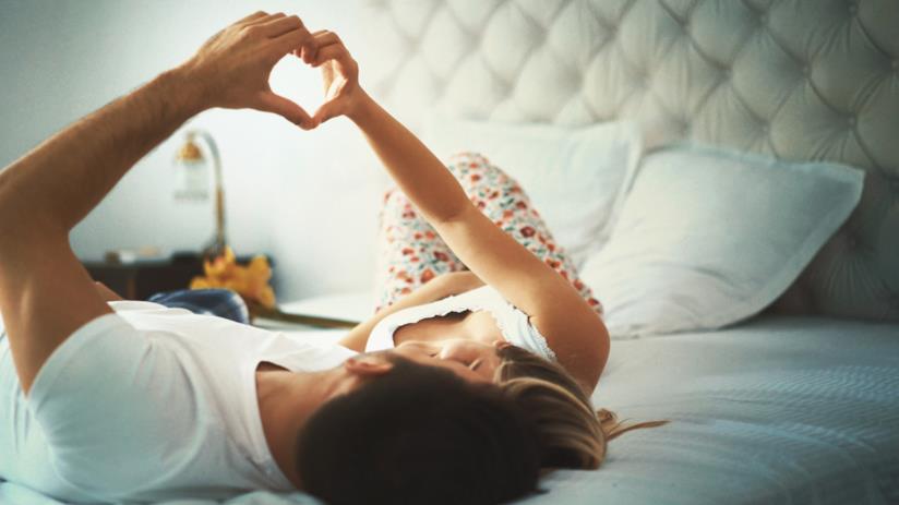 I modi vincenti per mantenere viva una relazione nel tempo Un uomo e una donna sdraiati sul letto si guardano negli occhi