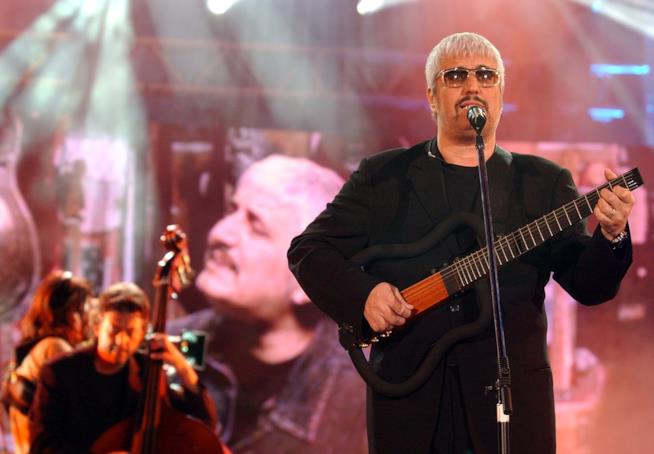 Resta quel che resta, brano inedito di Pino Daniele Pino Daniele, in nero, mentre suona la chitarra in piedi al microfono